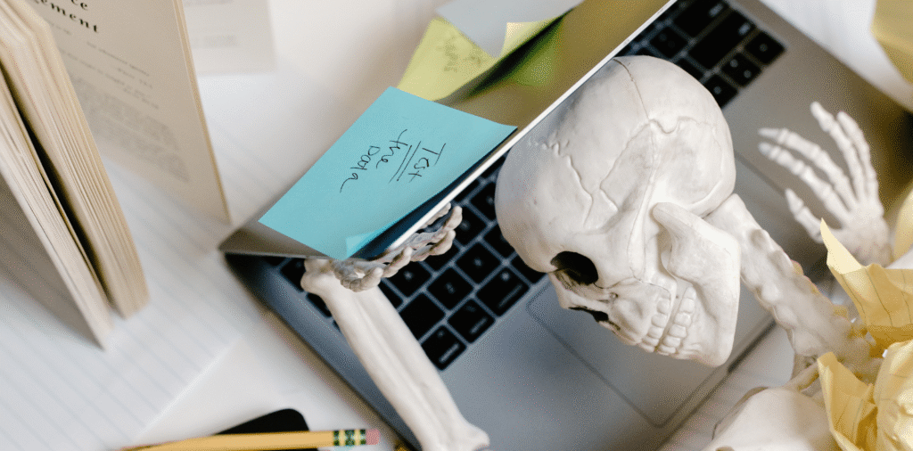 Woman laying down and journaling during a hike in the mountains. Her head is resting on her backpack and her journal rests against her legs. The scenery is rocky, with yellow grass and autumn trees.